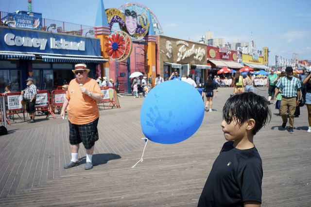 kid plays with a blue balloon on the Coney Island boardwalk